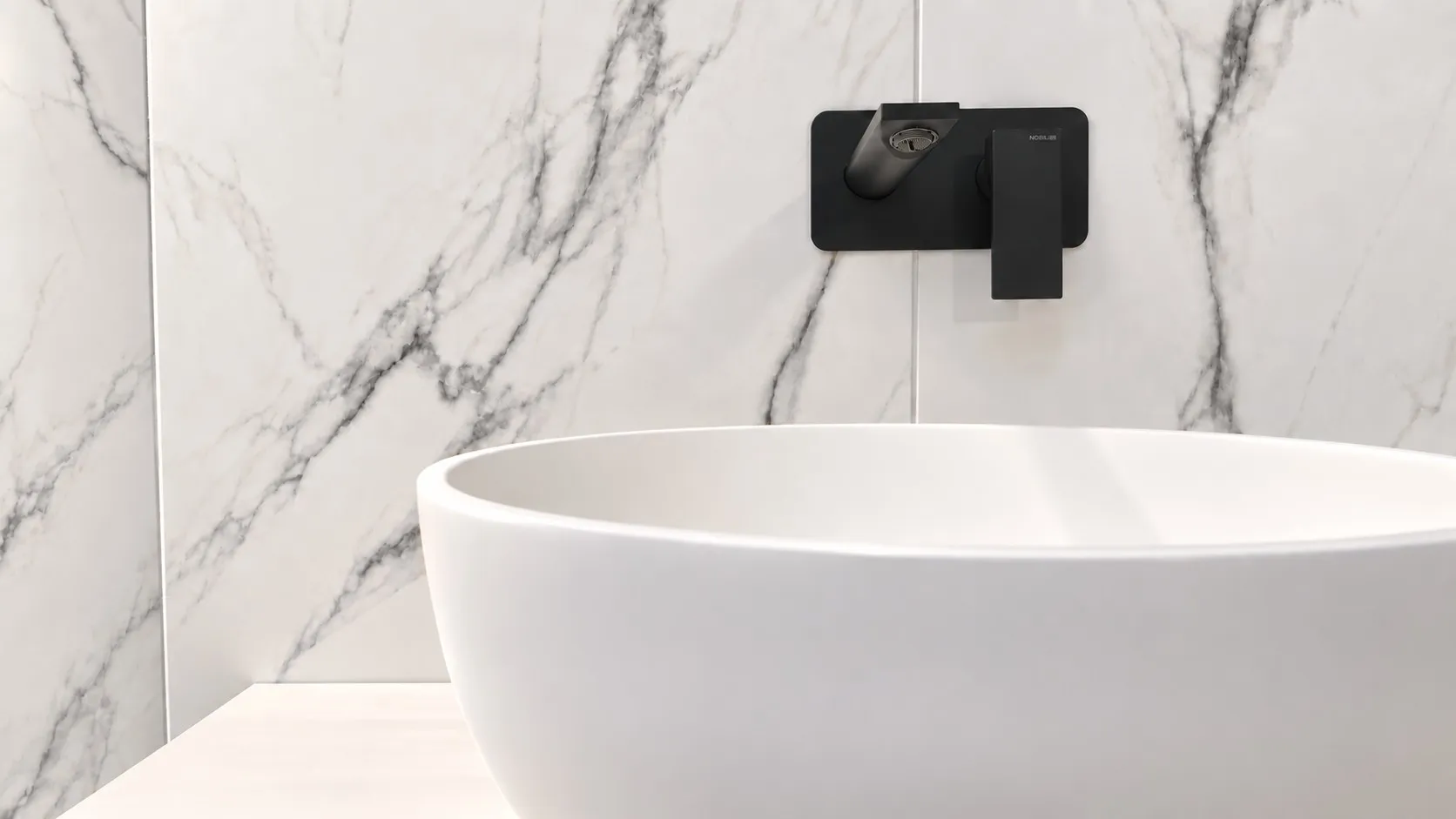 Bagno con lavabo d’appoggio bianco e rubinetto nero a parete su lastre effetto marmo