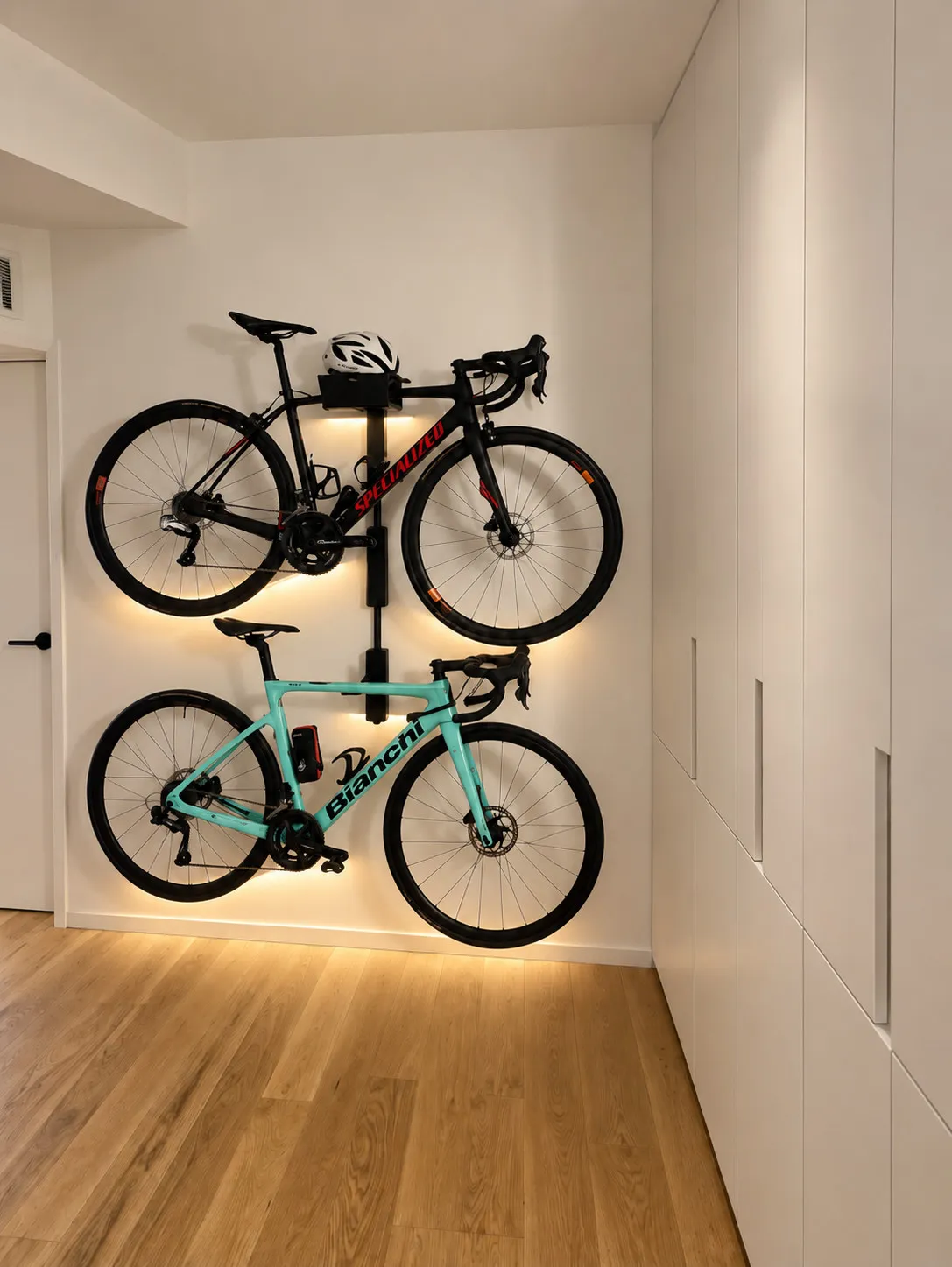 Disimpegno con armadi a muro bianchi a maniglie incassate e due biciclette appese a un supporto illuminato